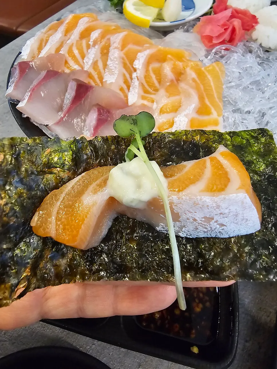 Salmon sashimi topped with sprouts on seaweed