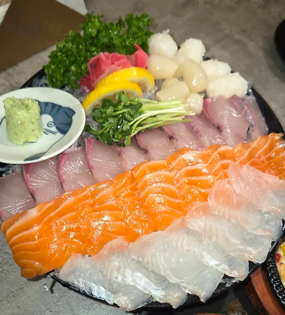 Plate of thick-cut aged sashimi topped with radish sprouts and lemon