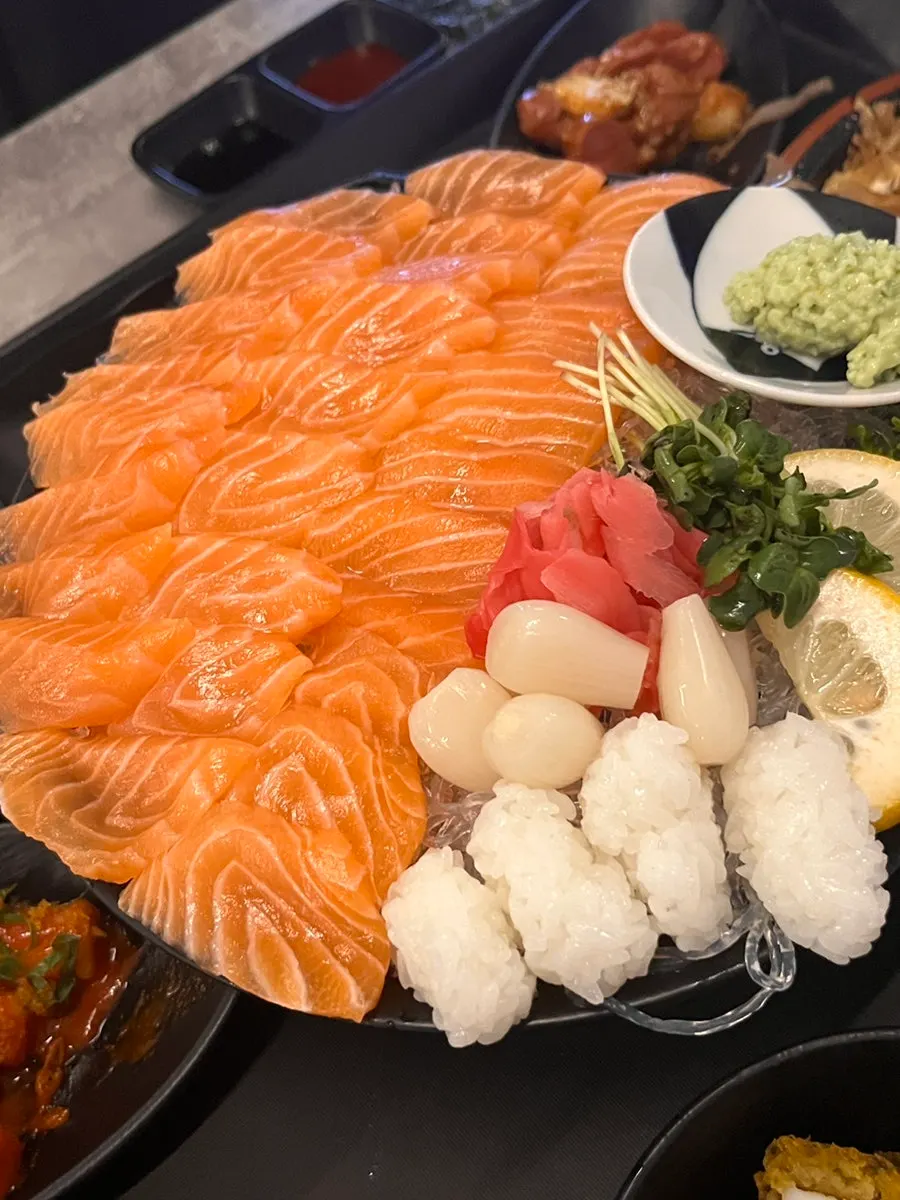 A piece of salmon sashimi held with chopsticks
