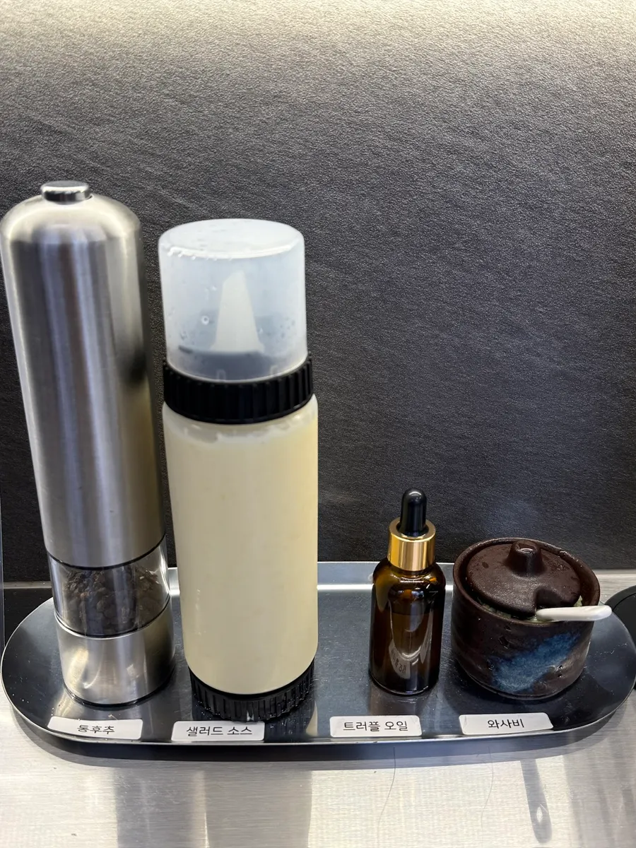 Condiment setup with whole peppercorn, salad sauce, truffle oil, and wasabi