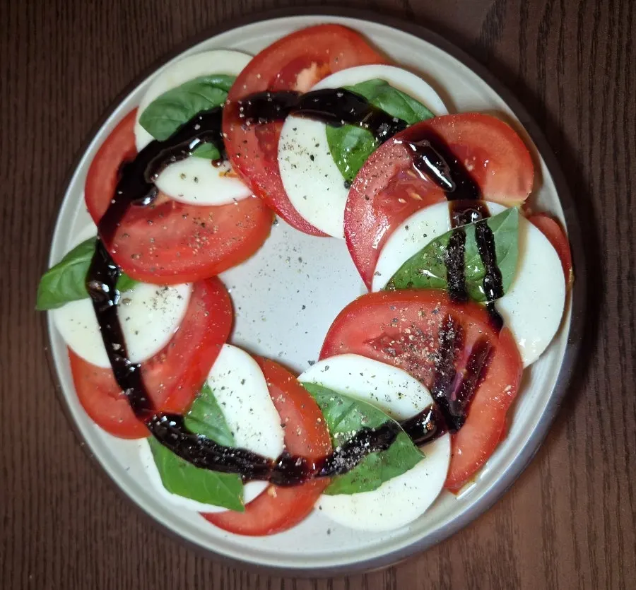 Caprese made with tomato, whole mozzarella, and basil