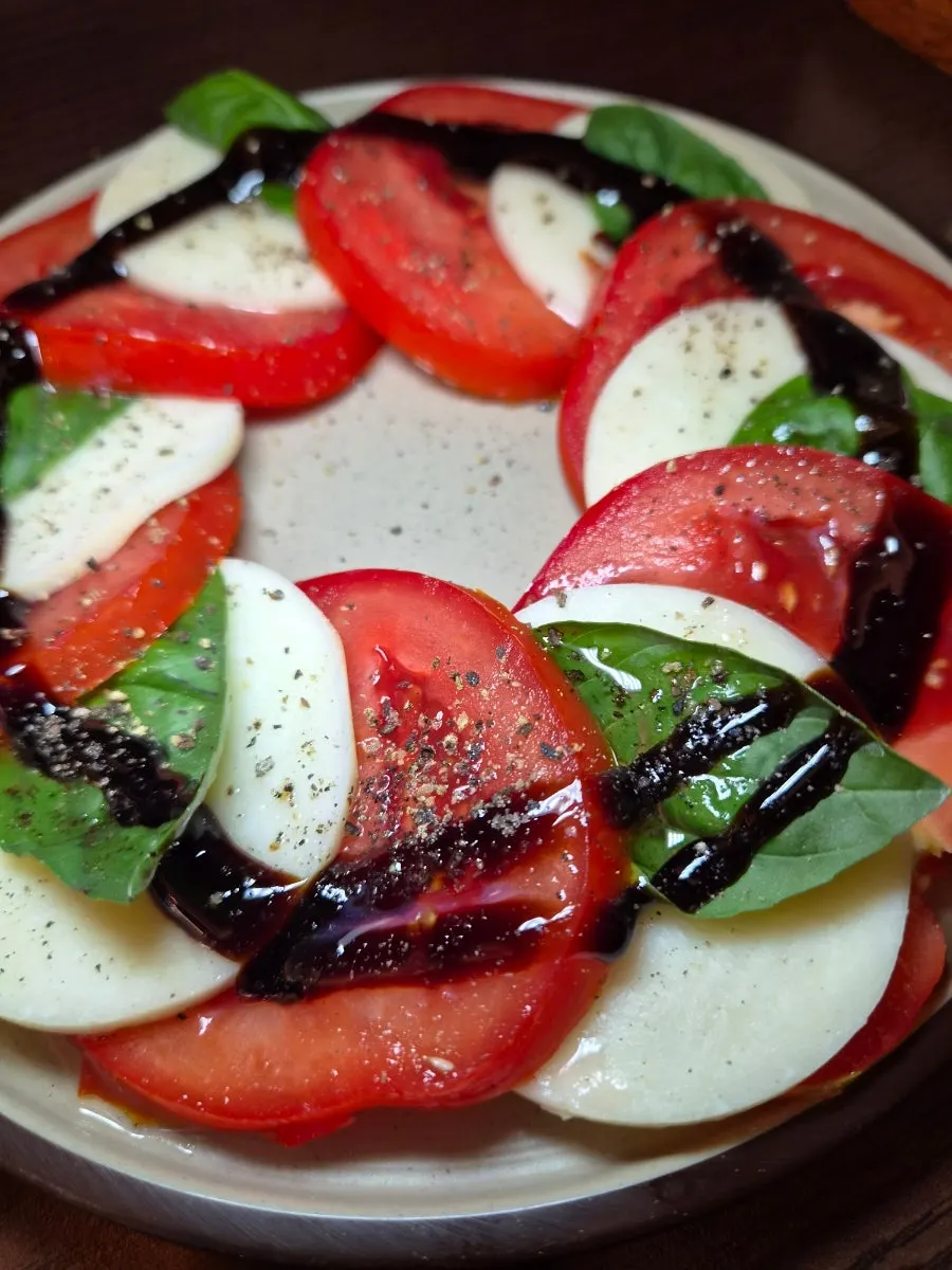 A plate of caprese with a tangy sauce