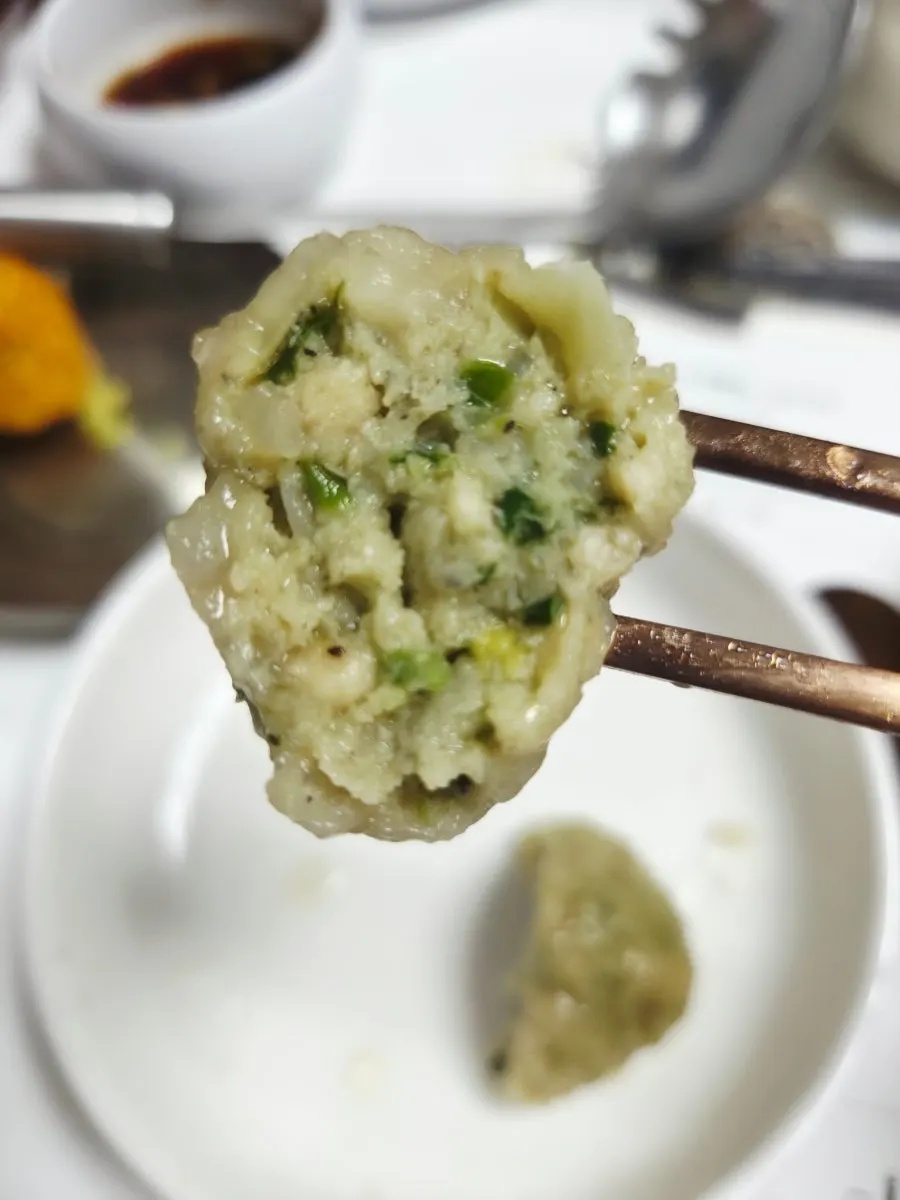 A rolled dumpling lifted out of the hot pot