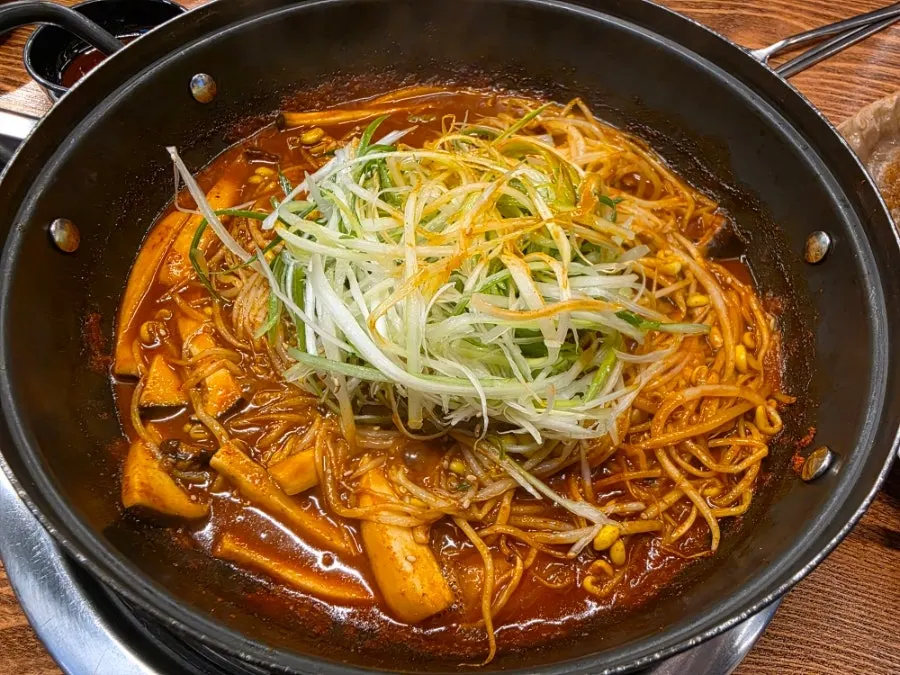 Pot of Jimidang's spicy braised ribs topped with bean sprouts and shredded scallions