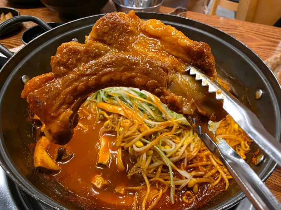 A large spicy rib lifted with tongs