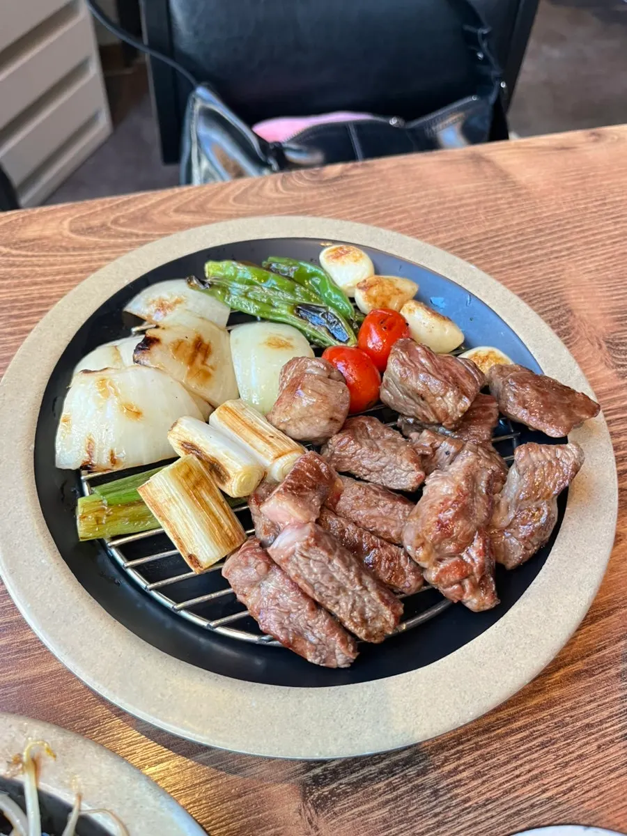 Staff member grilling lamb ribs tableside on the fire