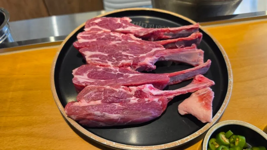 The lamb chops plated raw before grilling