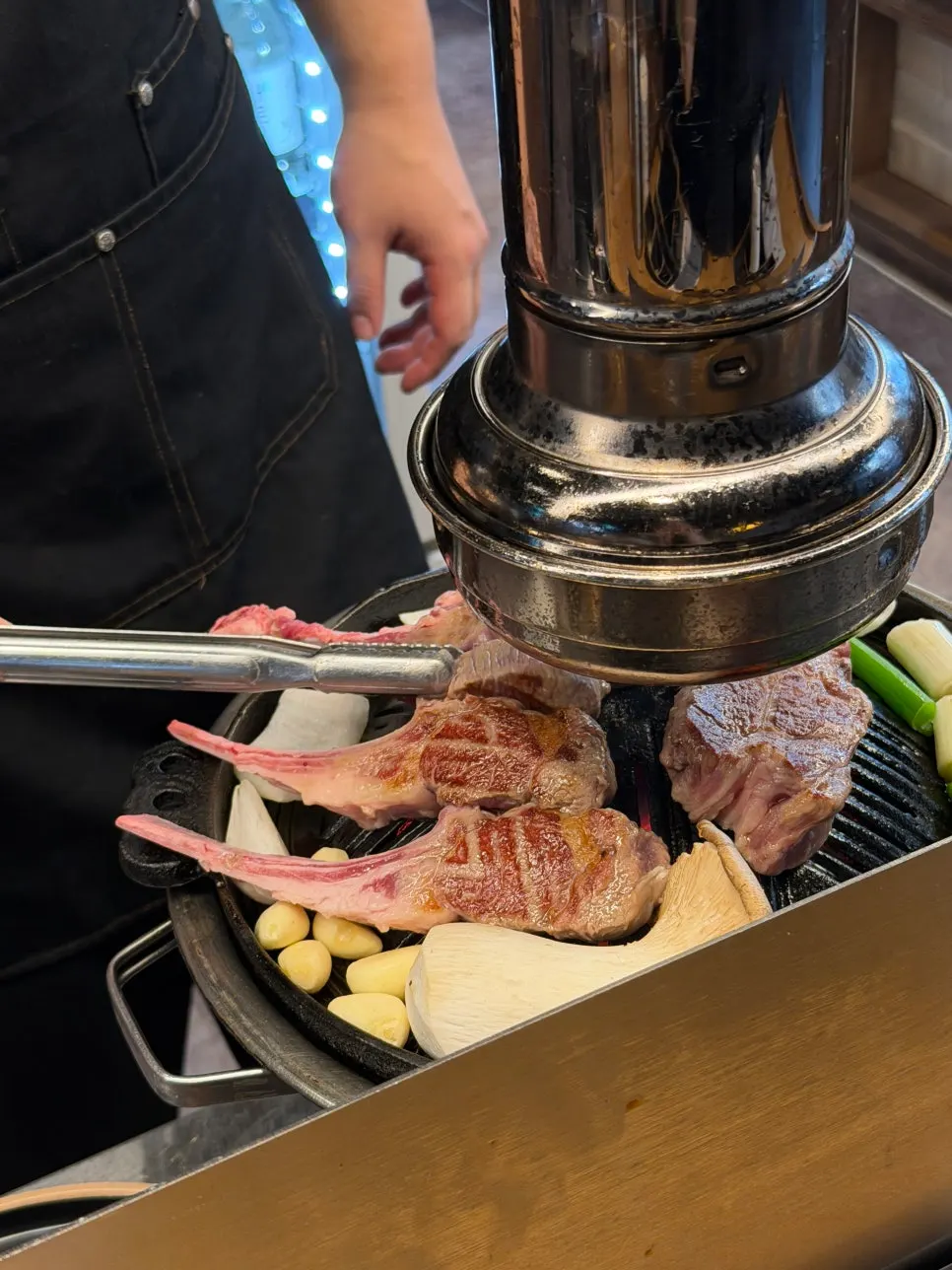 Grilling lamb over the charcoal fire beyond the splash guard