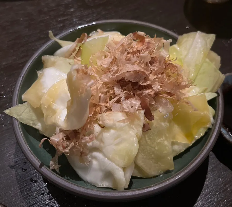 Complimentary cabbage salad topped with bonito flakes