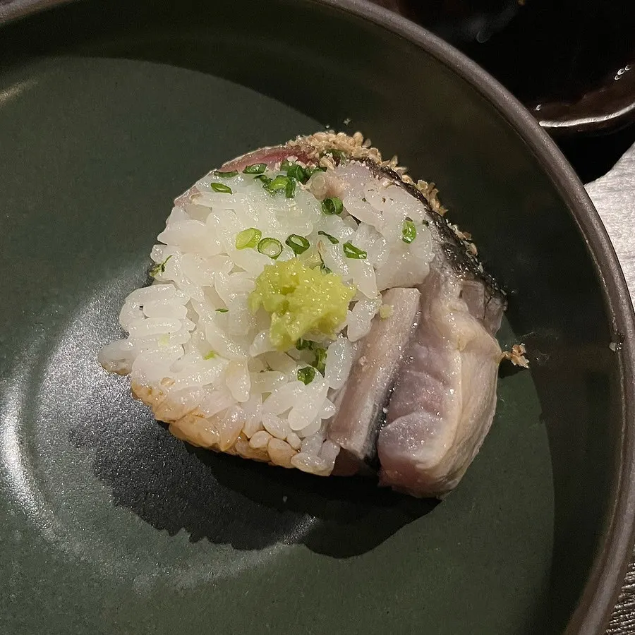 Heavy piece of mackerel pressed sushi lifted with chopsticks