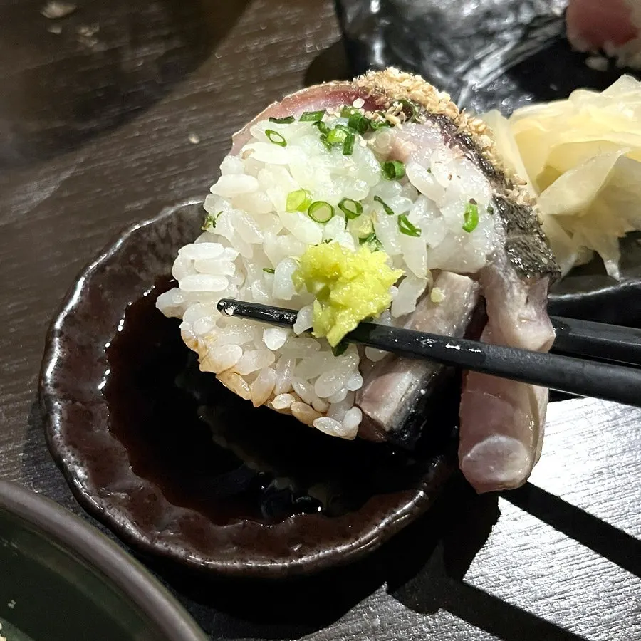 A piece of mackerel pressed sushi topped with wasabi