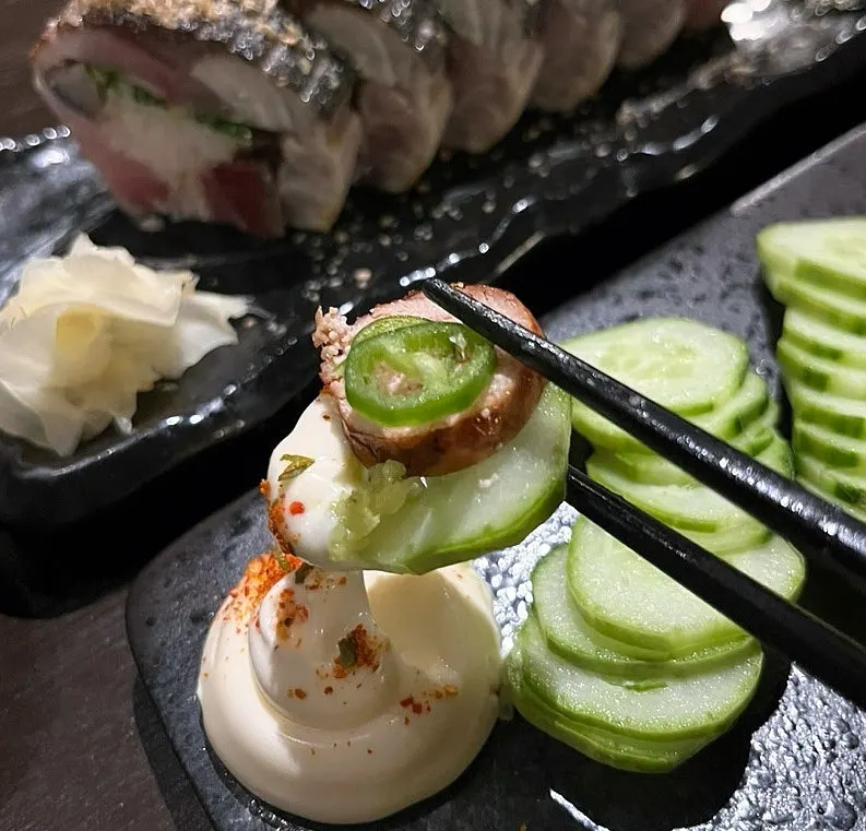 A bite of pollock roe topped with mayonnaise and chili