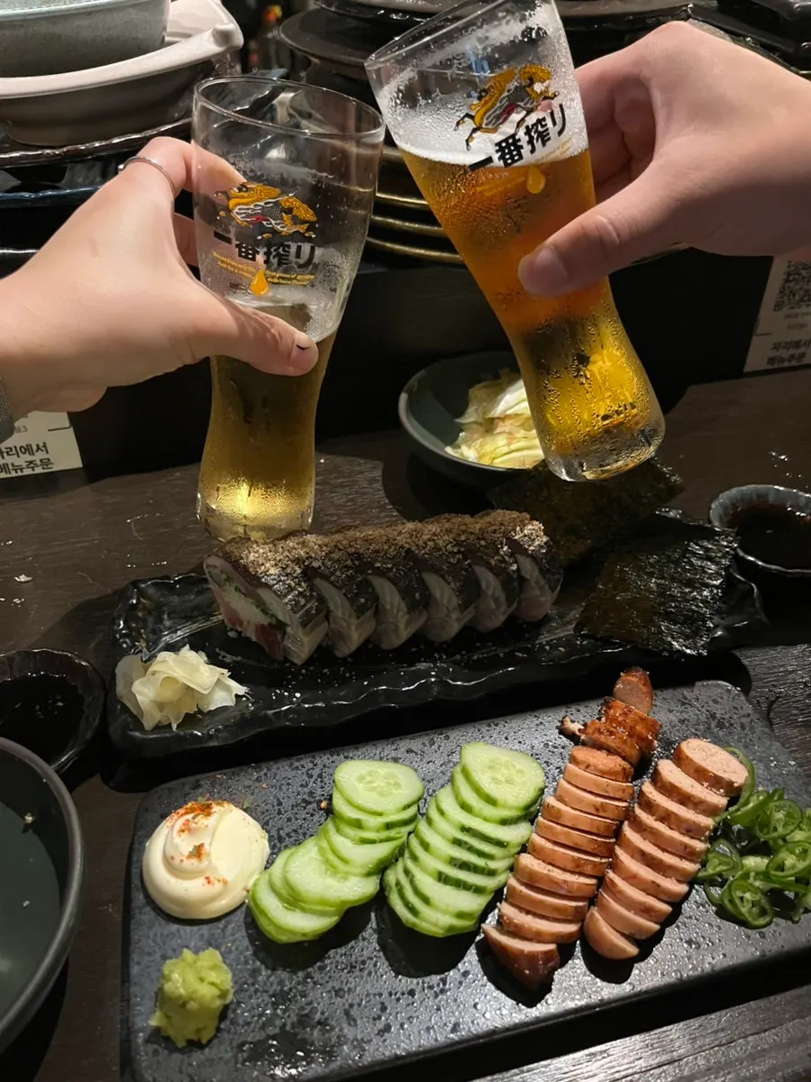 Draft beer served alongside mackerel pressed sushi and grilled pollock roe
