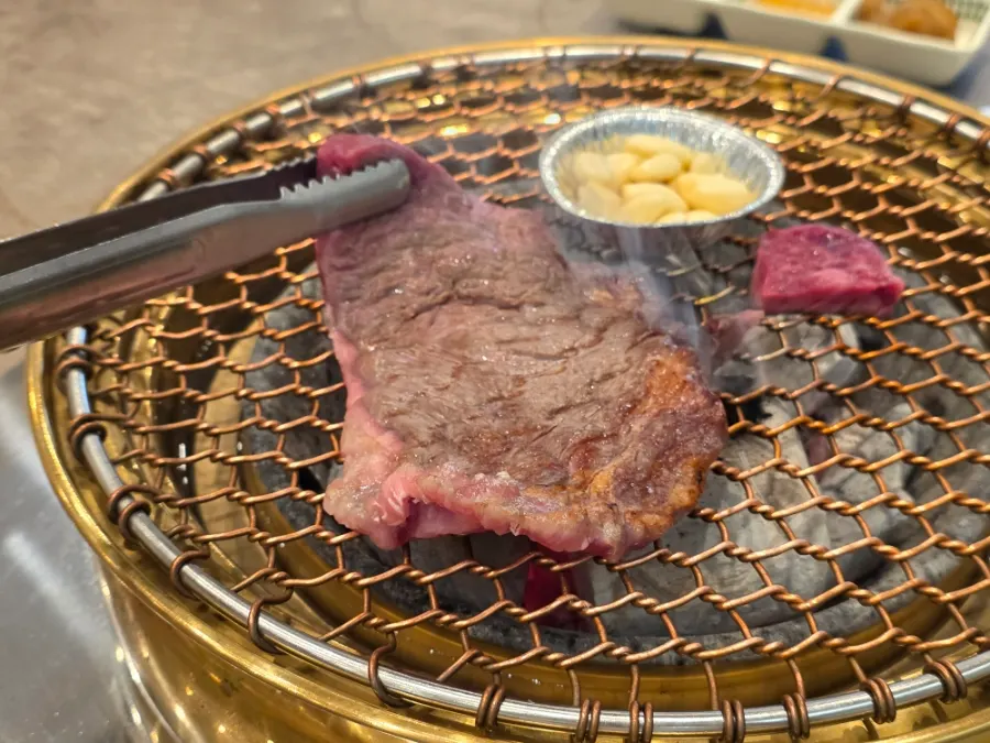 A piece of flower marbled ribeye grilling over charcoal
