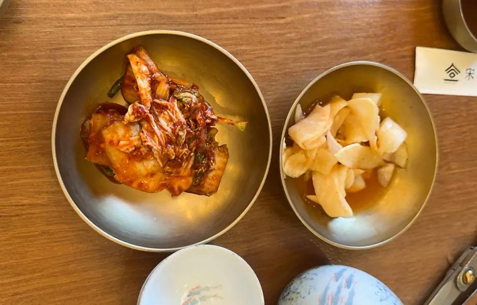 Kimchi and pickled radish side dishes served at the table