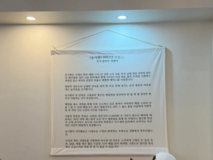 Sign introducing Song Giwon Jinju Naengmyeon's broth and buckwheat noodles