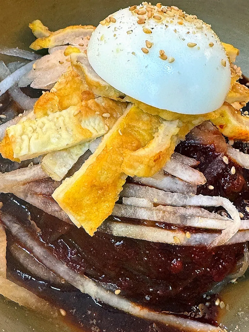 Bibim-naengmyeon topped with yukjeon and radish salad