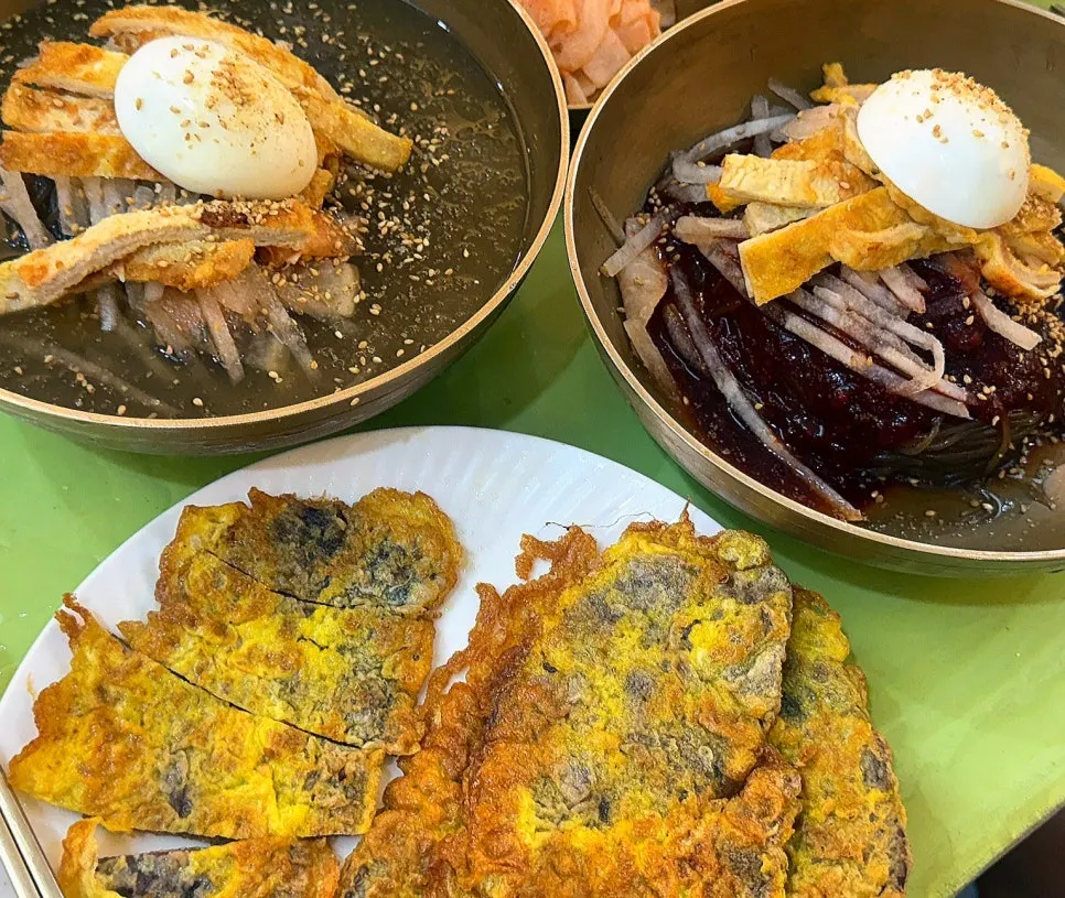 A table set with mul-naengmyeon, bibim-naengmyeon, and yukjeon