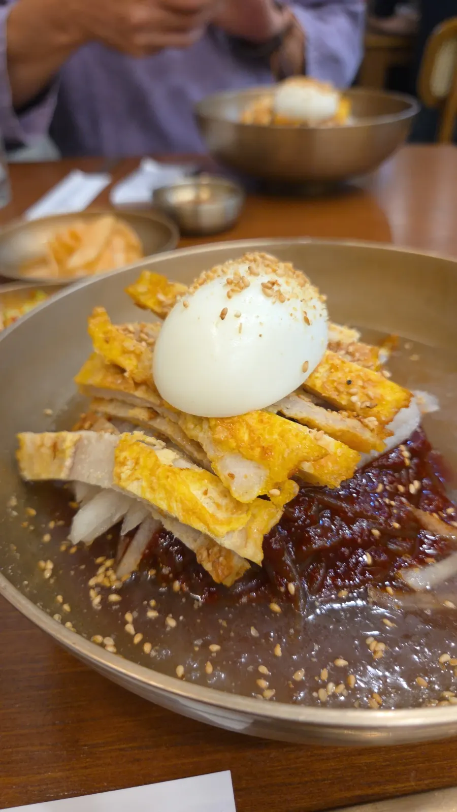 A bowl of mix naengmyeon topped with yukjeon, pear, and special sauce
