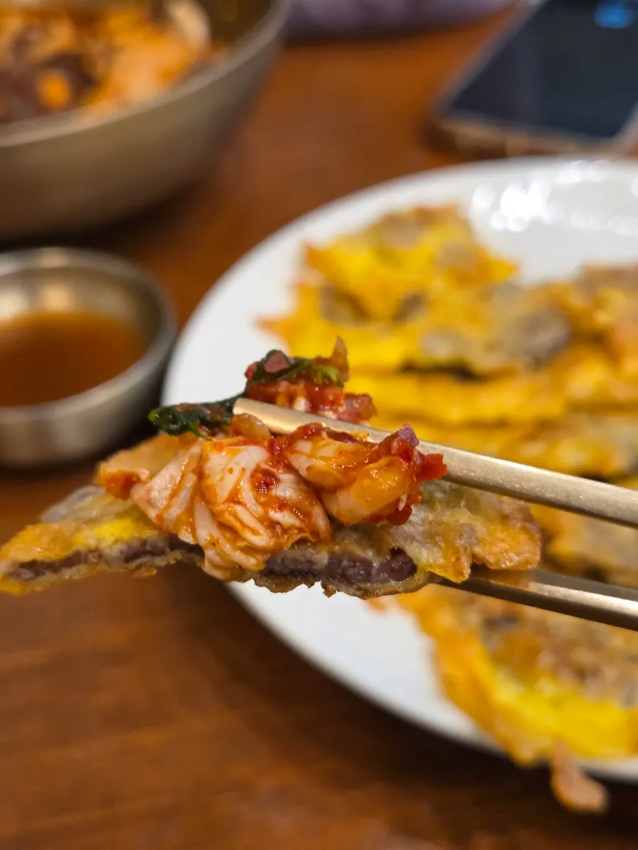 A piece of yukjeon placed on top of kimchi