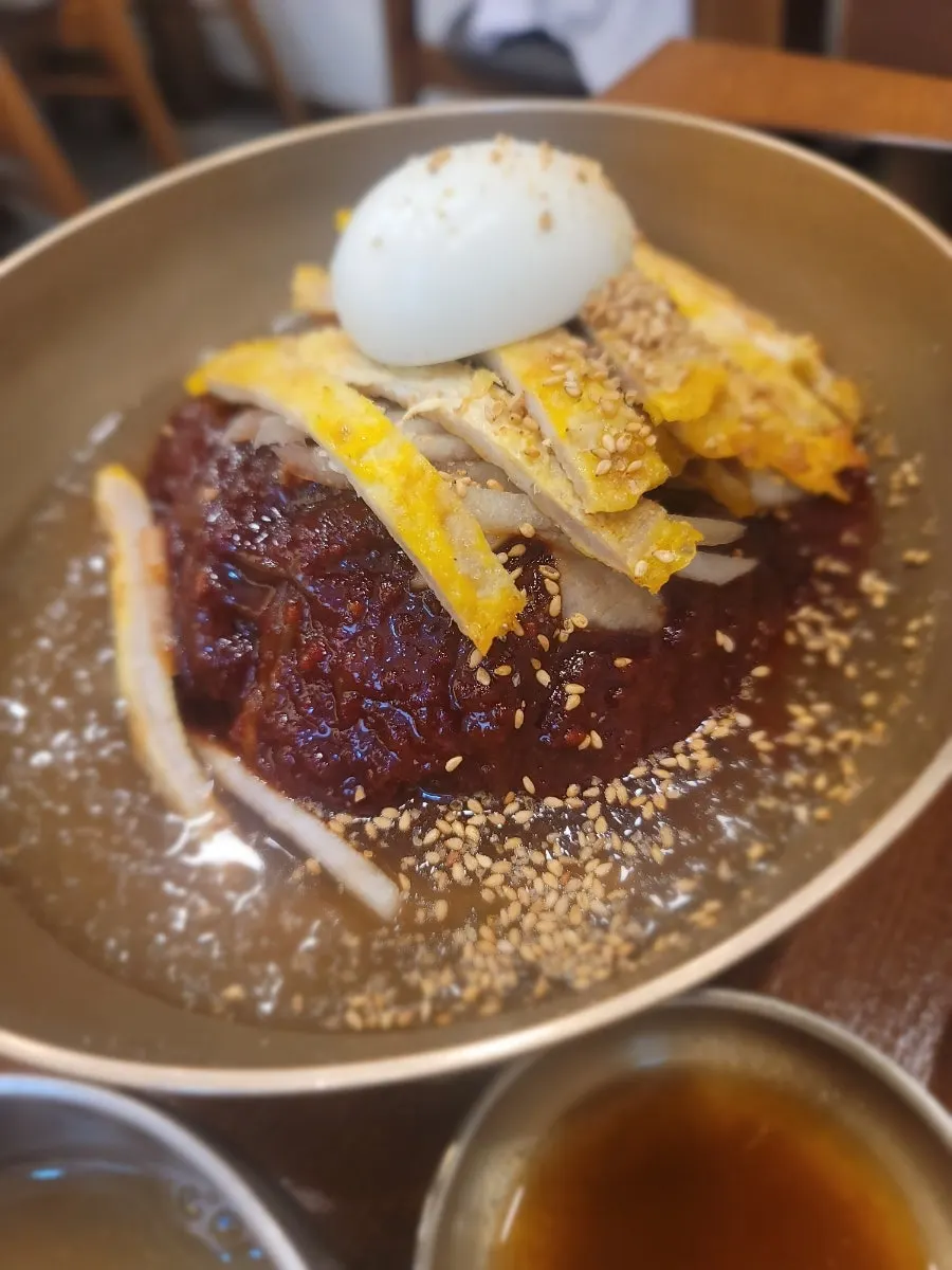 Seokkeo-naengmyeon topped with yukjeon garnish