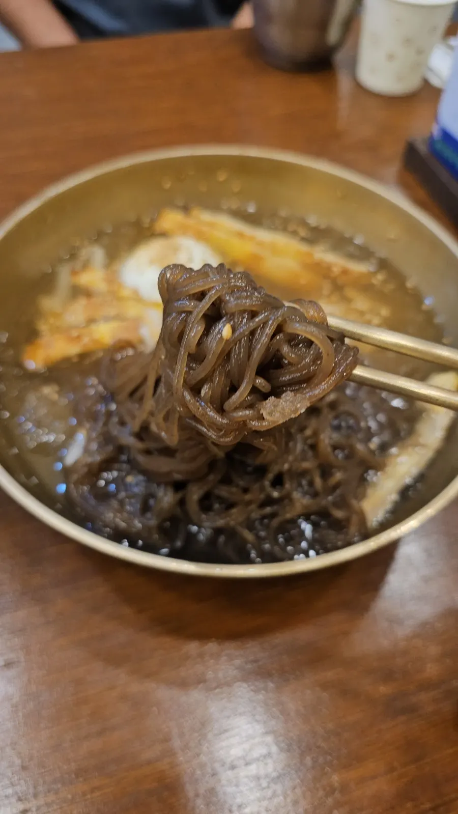 Fideos de naengmyeon de agua levantados con los palillos