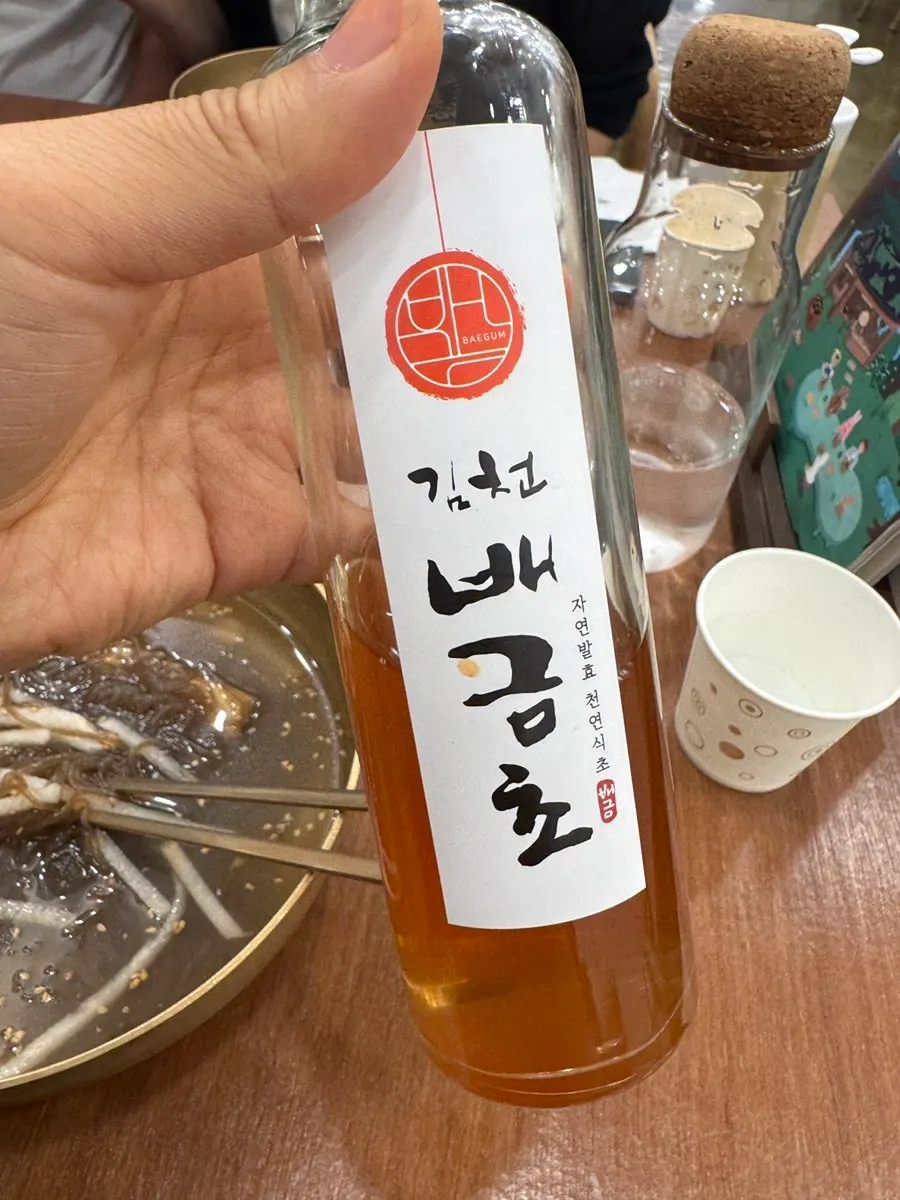 Vinegar bottle placed next to the naengmyeon bowl on the table