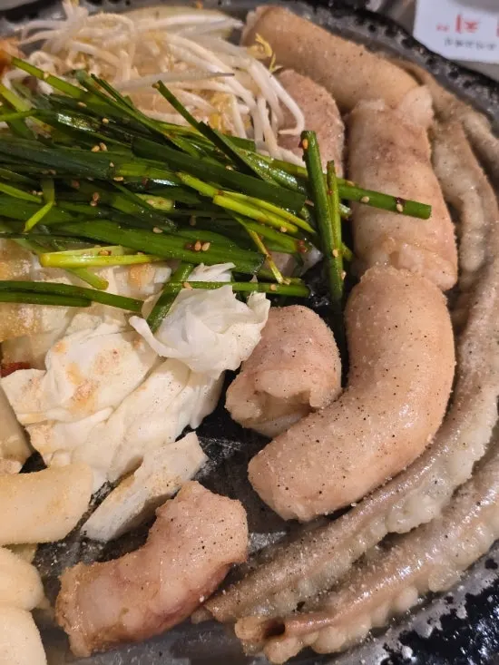 Gopchang grill pan with rice cake sticks, chives, potato, and kimchi