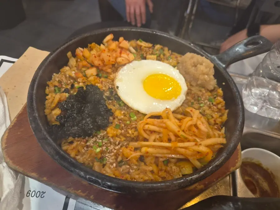 Kkakdugi fried rice on an iron plate topped with fried egg and seaweed flakes