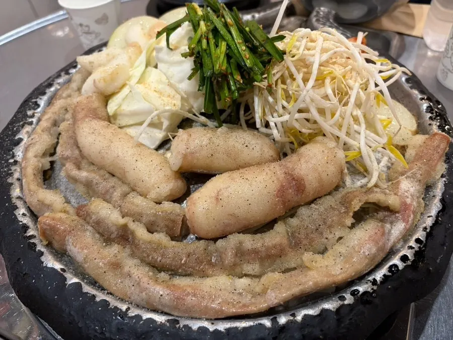 Beef gopchang and daechang served with cabbage, bean sprouts, scallion strips, and potato