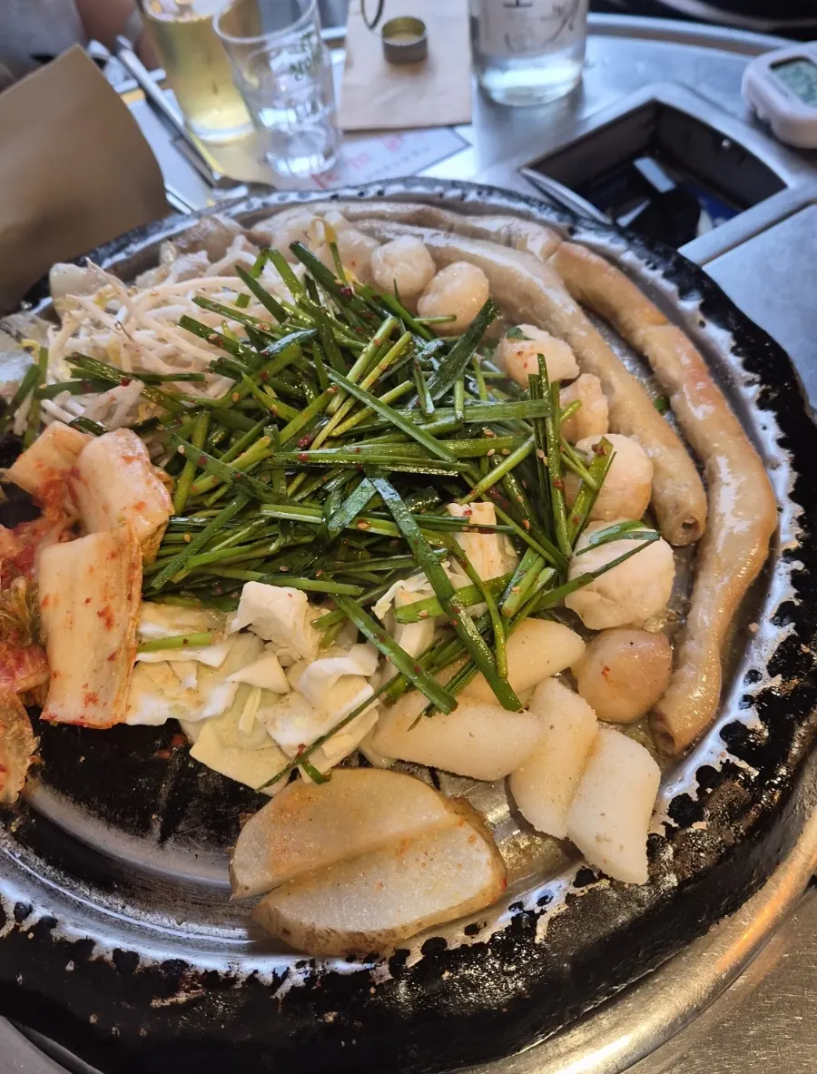 A piece of gopchang dipped in minari pickle sauce
