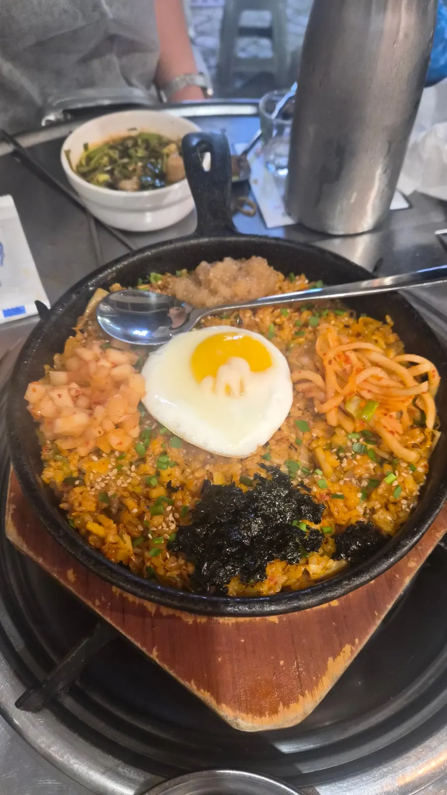 Kkakdugi yangbap on a hot plate topped with a soft fried egg