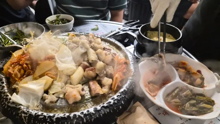 Grill topped with bean sprouts, cabbage, rice cake, and potato