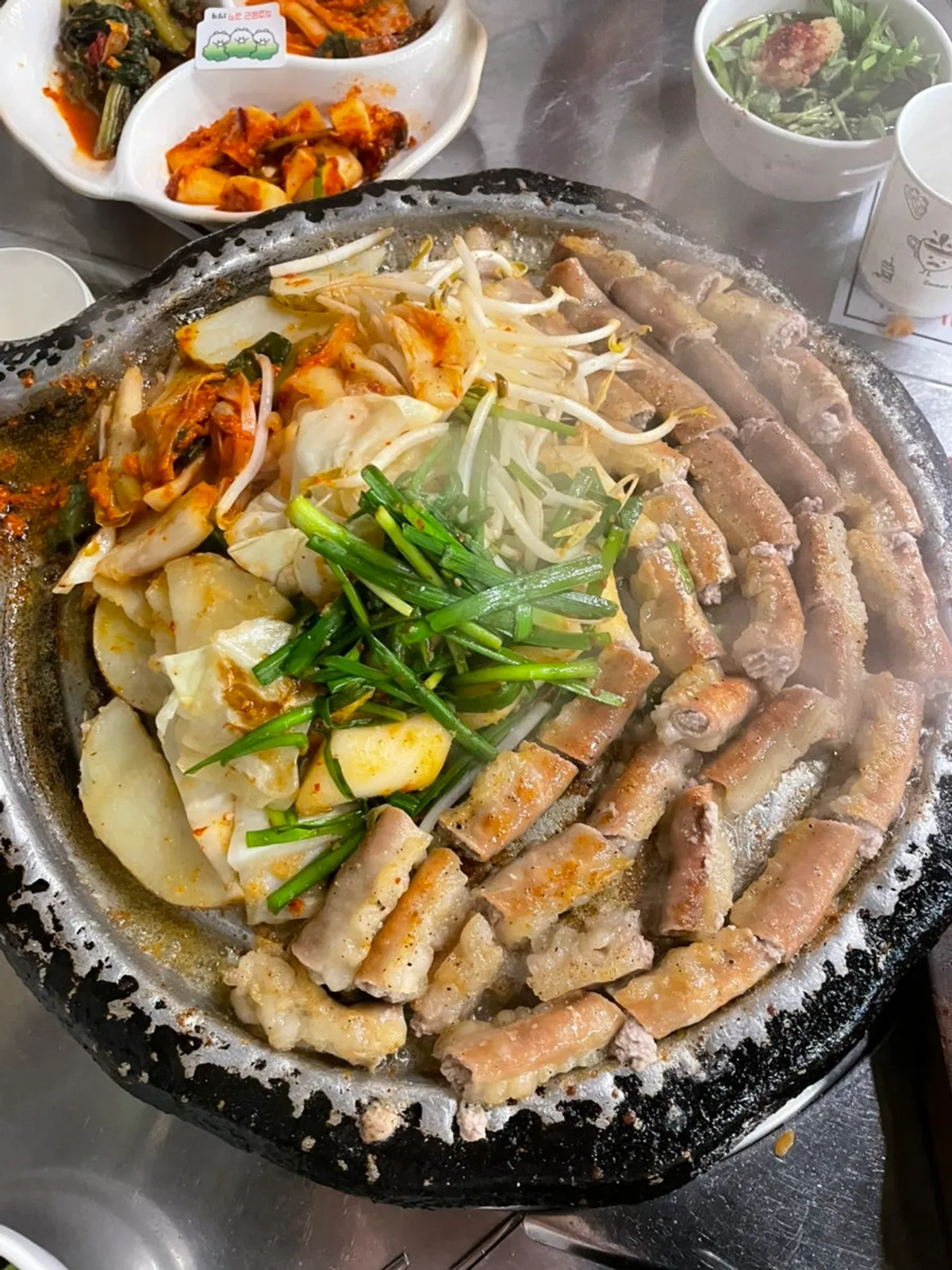 Hanwoo gopchang grilling on the plate with kimchi, potato, and rice cake