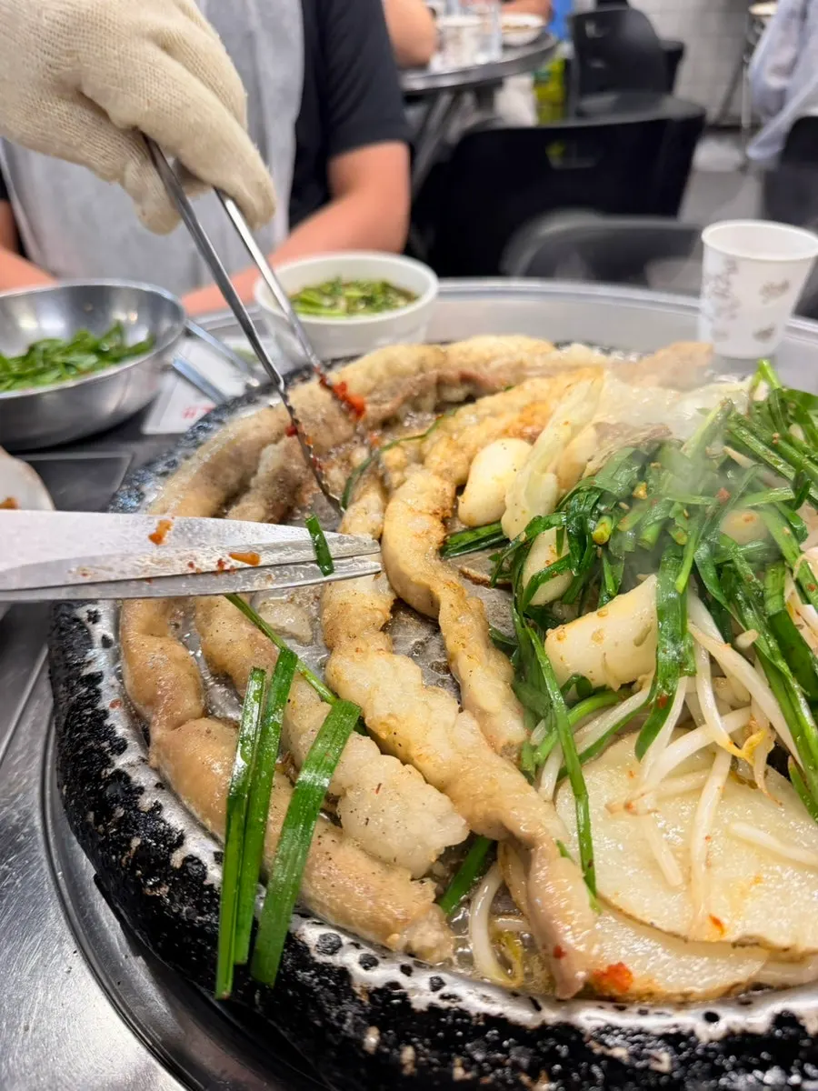 Staff member grilling the gopchang as it cooks on the grill