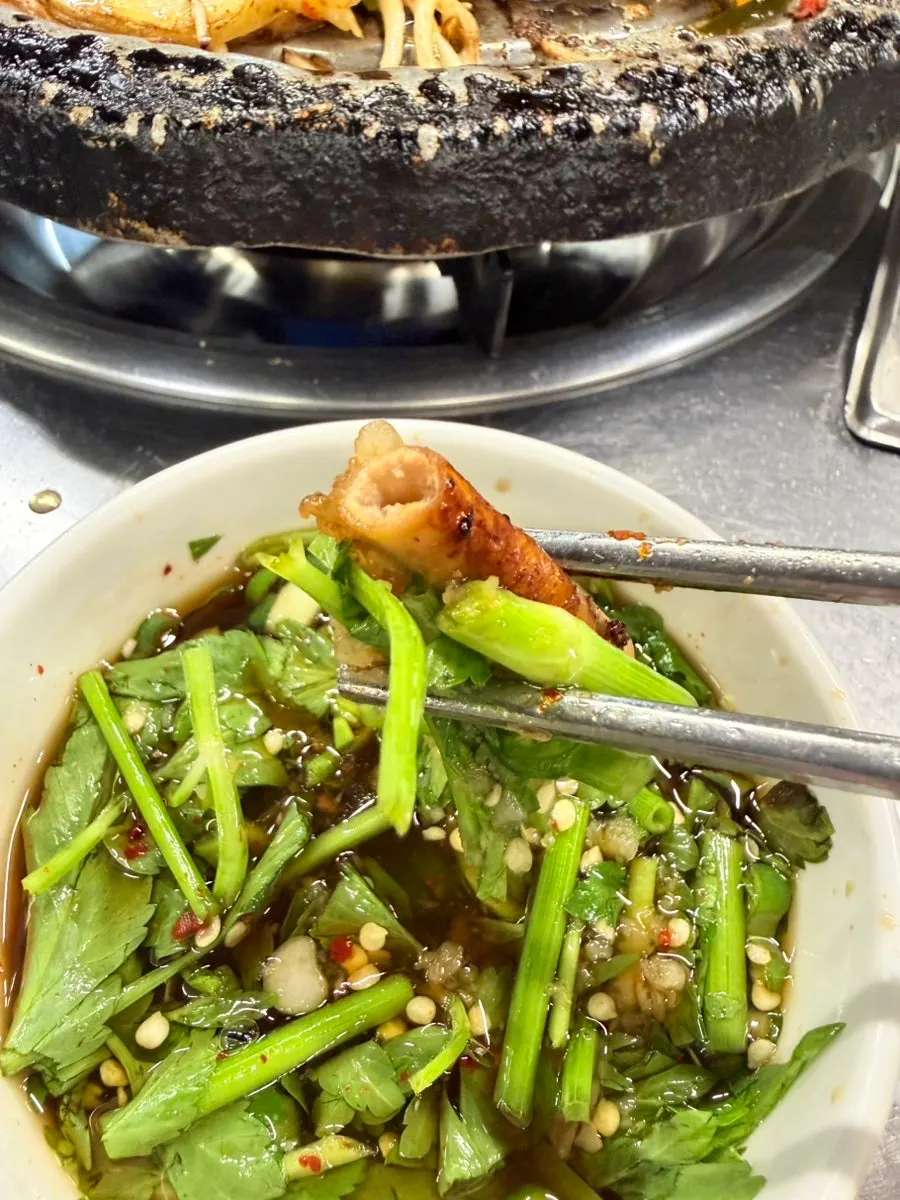 Gopchang dipped in the minari-pickled garlic sauce