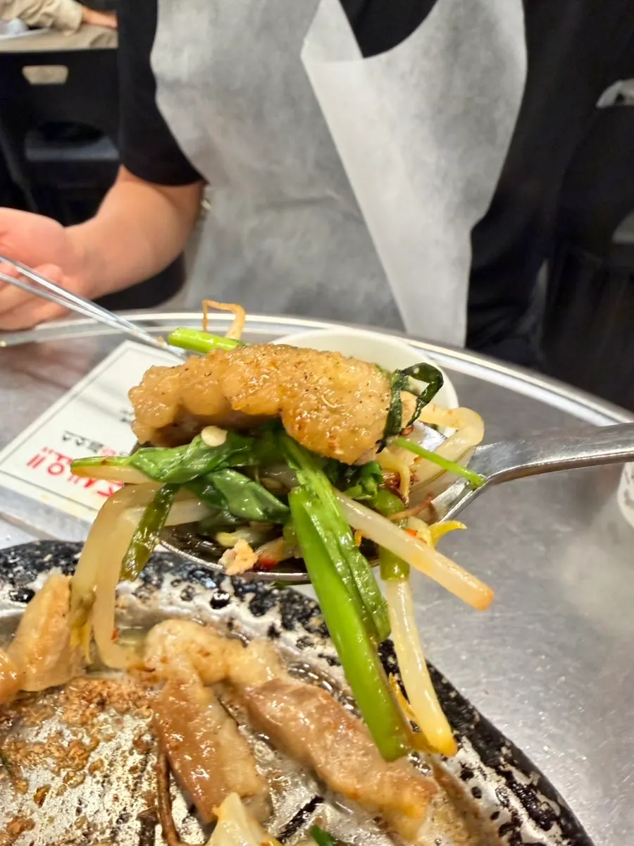 A bite combining gopchang, mung bean sprouts, and rice cake