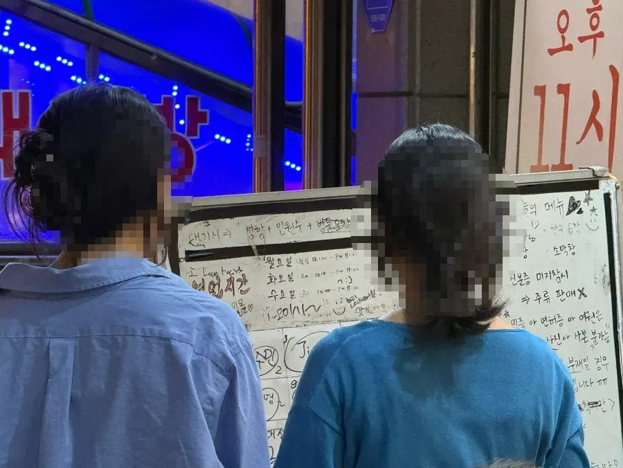 Whiteboard outside the restaurant where customers write their names for the waitlist