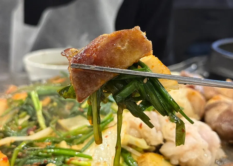 A bite paired with grilled chive salad and sauce