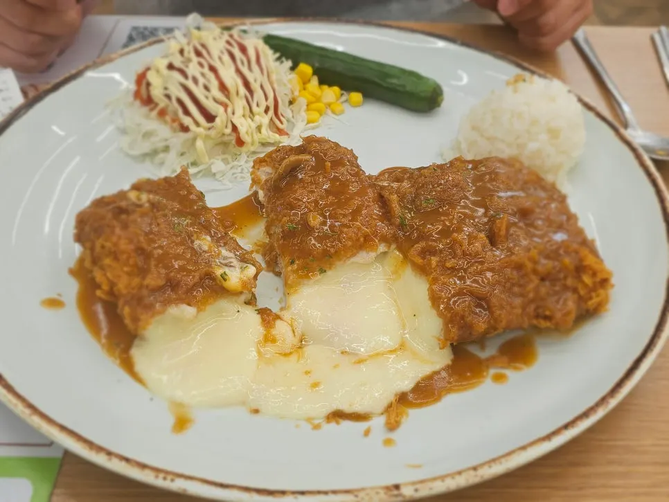 A piece of Cheese Waterfall Katsu with cheese stretching from it