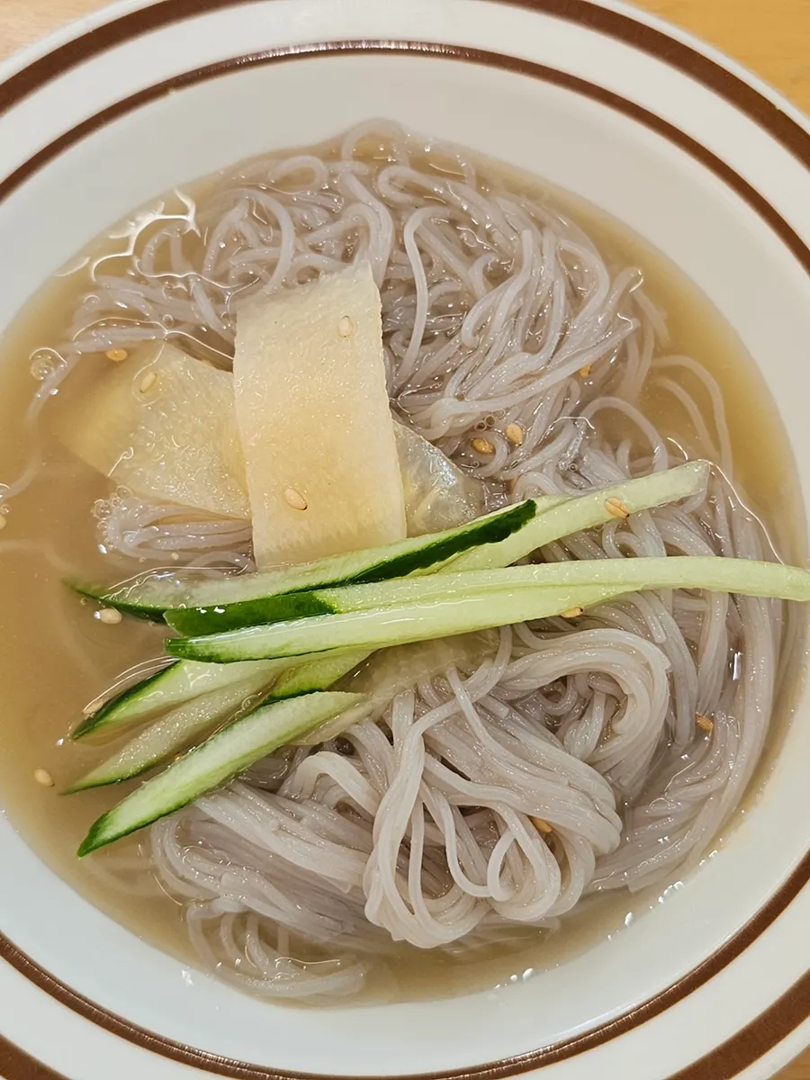 Lifting up a strand of mul-naengmyeon noodles