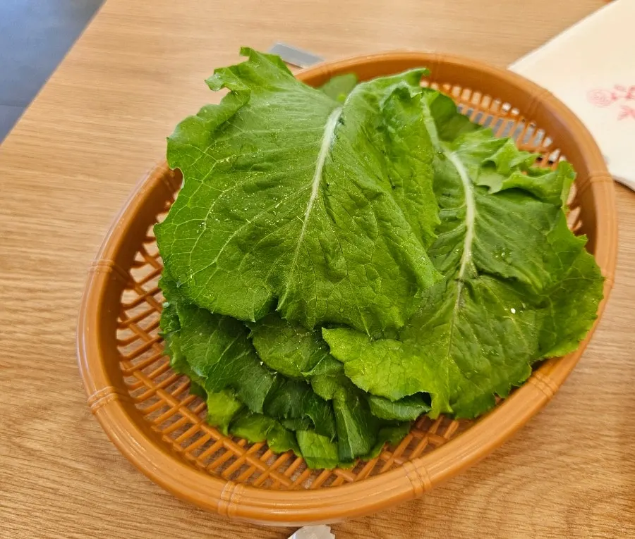 A bite of wang donkkaseu wrapped in fresh vegetables