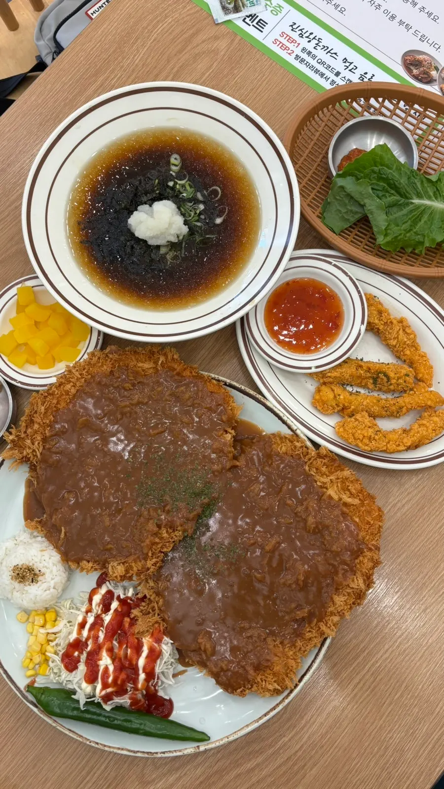 Mesa servida con Jinsimwang Double Donkatsu, naengmomil y chicken tenders