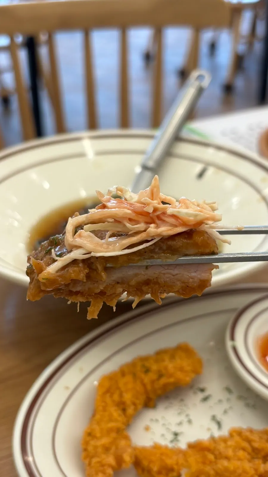 Corte de una porción de donkatsu grande sostenida con palillos
