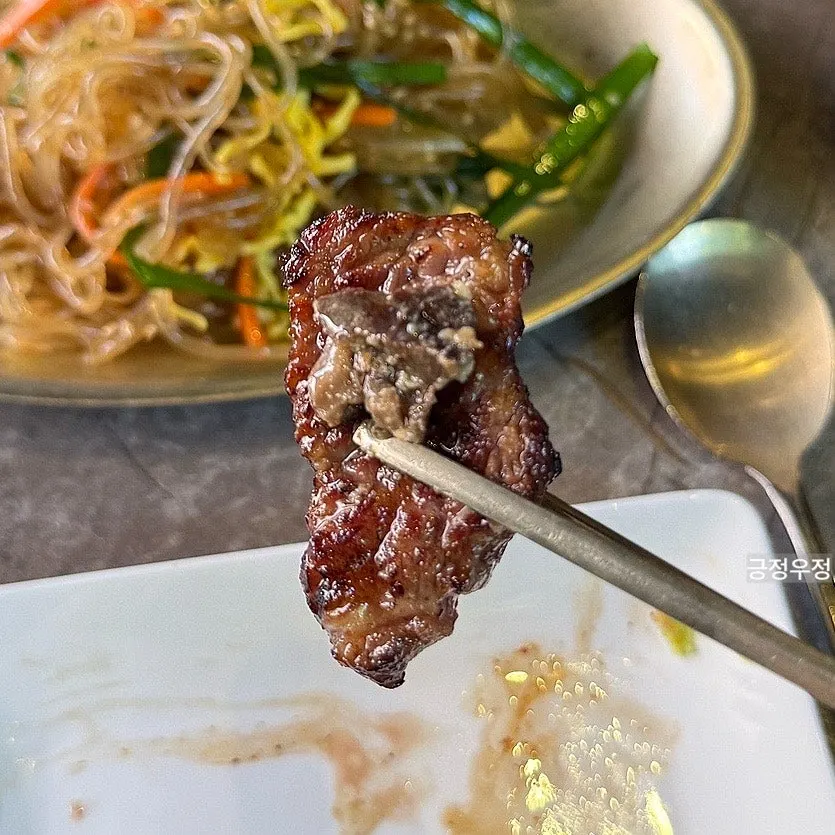 A piece of woodae galbi dipped in sauce