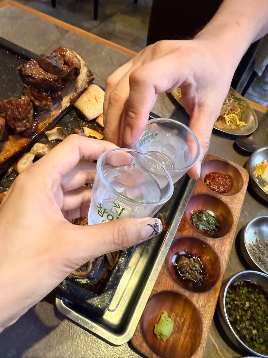 Soju glasses set beside the grilled meat