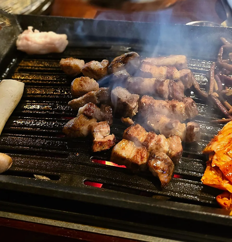 Straw-fired pork belly grilling over the brazier