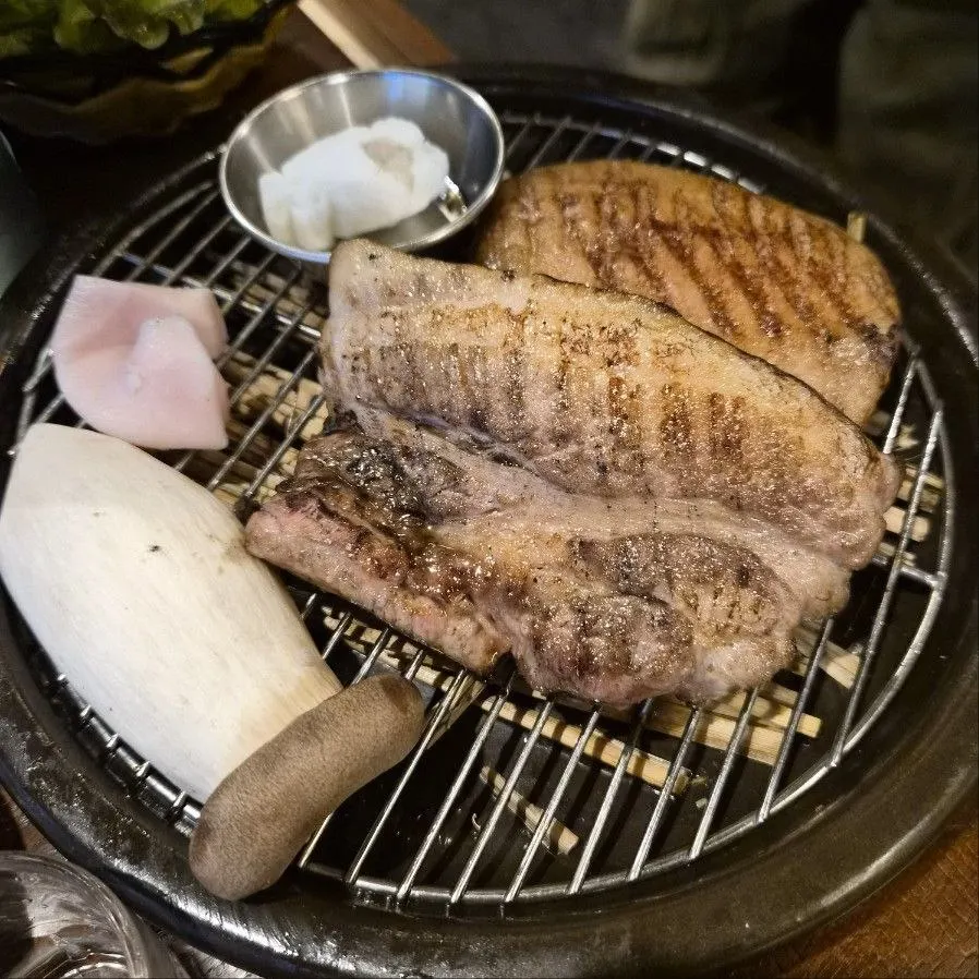 Staff grilling thick pre-seared straw-fire meat