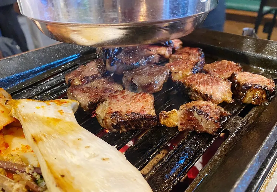 Prime rib being grilled again over charcoal