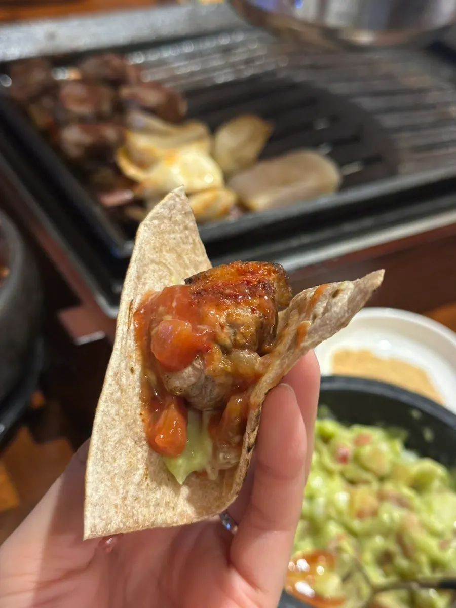 Tortilla with meat added on top of guacamole